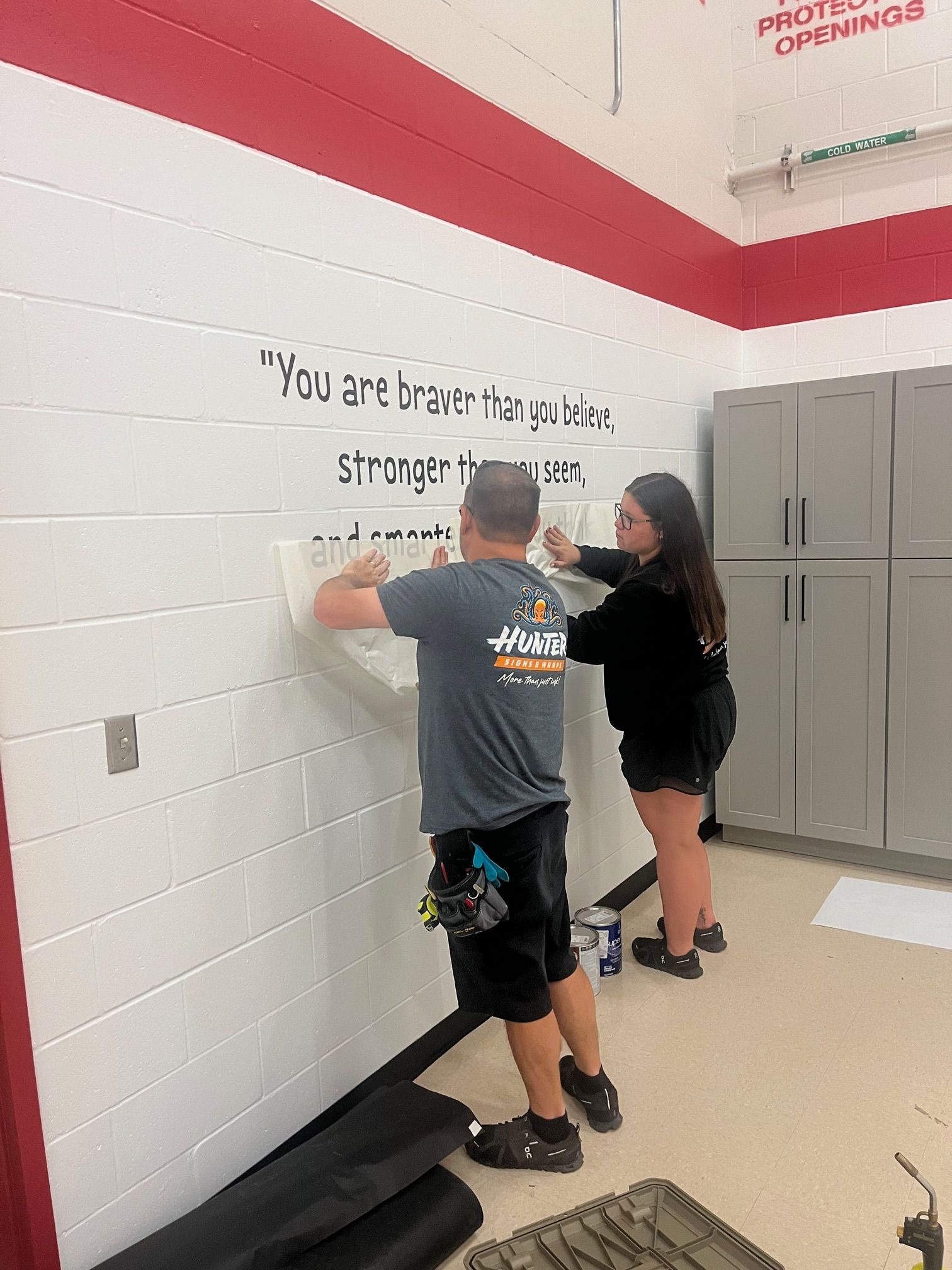 two people hanging a sign on the wall